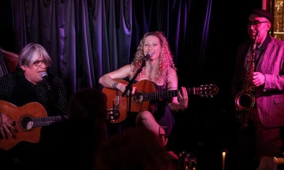 Three musicians on stage, two with guitars