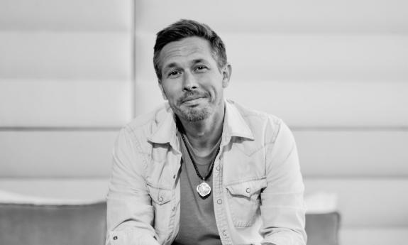 Songwriter Nick Norman sitting in front of a white wall