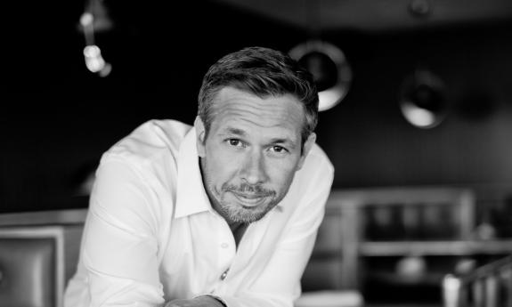 Singer songwriter Nick Norman leaning on bar, smiling