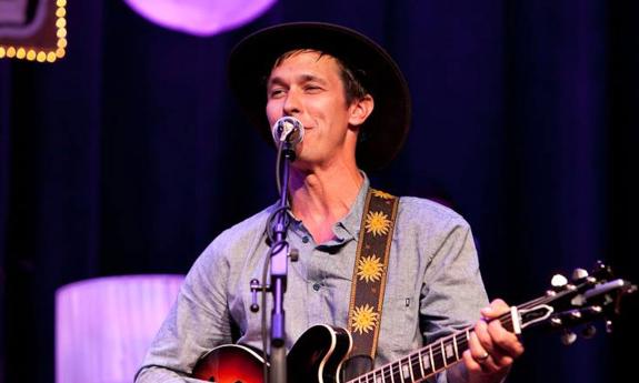 Singer songwriter Nick Norman at microphone, playing guitar