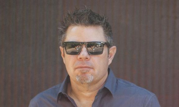 Songwriter Rodney Clawson in sunglasses, standing in front of a brown wall