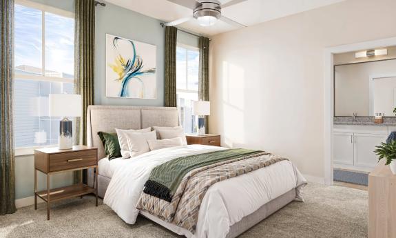 A master bedroom with creamy walls and a soft green decor opens to an en suite