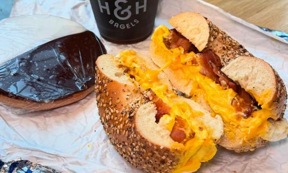 A bacon, egg, and cheese bagel sandwich with a cookie to the side