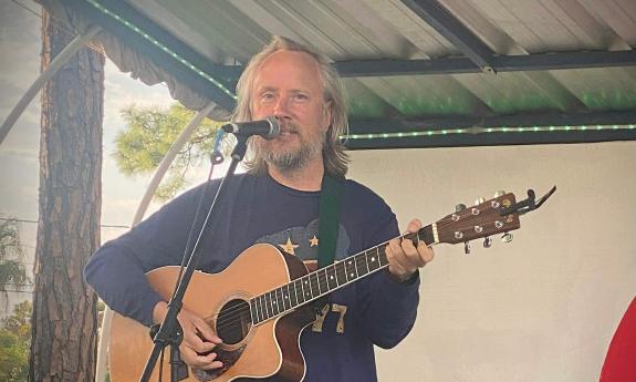 Solo performer Kilo on stage with his guitar in an outside venue
