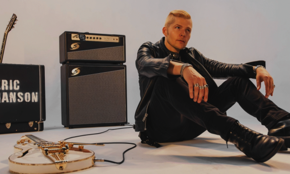 Eric Johanson wears black clothing and poses in front of a grey backdrop.