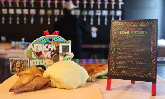 Food and a menu from African Love Kitchen on the bar at Global Bites
