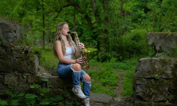 A young girl playing the saxophone outside