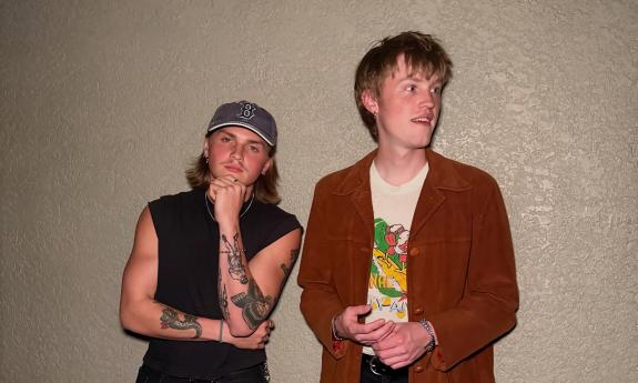 MAK, a duo standing against a beige wall