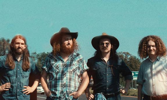 Four members of the band Mojohand standing outside