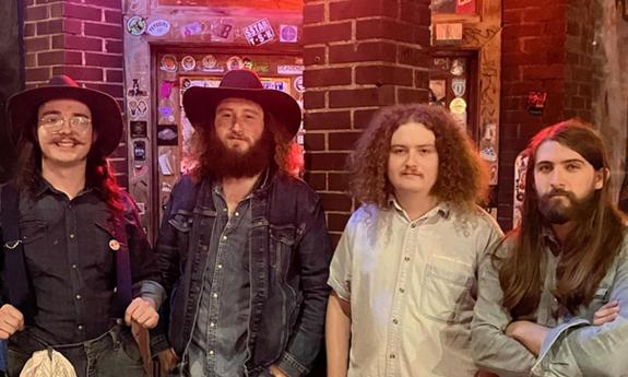 Four members of the band Mojohand standing together, onstage