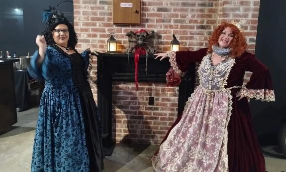 Two women, dressed in garb from the 1700s greet guests at the Blackbeard's Ball