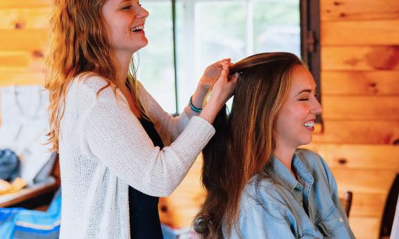 A hair stylist braiding a woman's hair