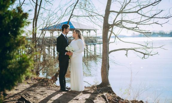 A bride and groom standing on the edge of water