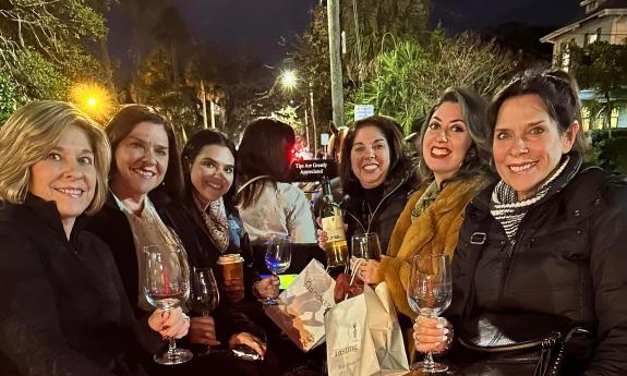 Six women in a large open carriage enjoying wine as they view the lights