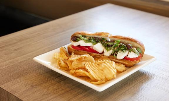 Caprese sandwich featuring mozzarella and tomatoes on a sub roll with a side of potato chips