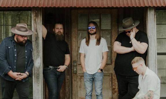The band Feverdreams standing on a porch of an old house