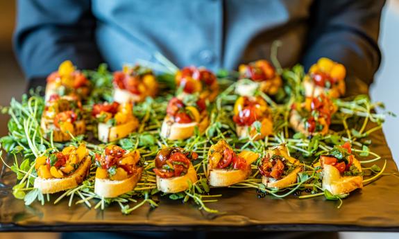 A server holds a tray of bruschetta for event guests