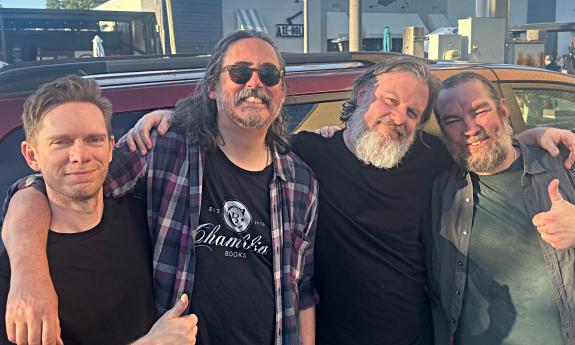 The four members of Chimes standing outside near a van