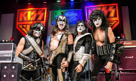 Members of Kiss Alive the Tribute standing next to gear on stage
