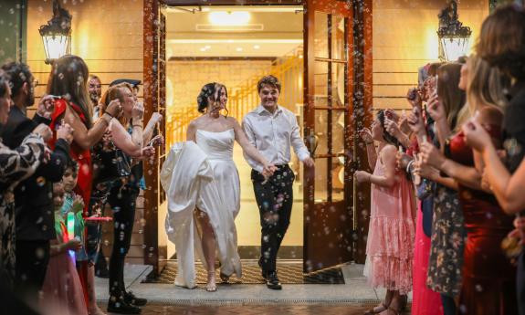 A bride and groom exiting their wedding, greeted with their guests blowing bubbles