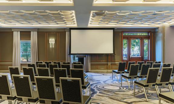 A meeting room arranged for theatre seating with a whtie screen at the front