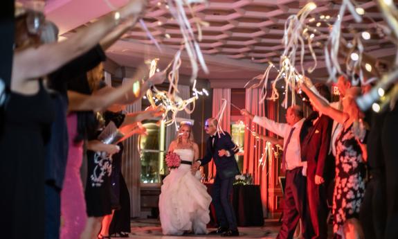 A bride and groom at the start of a friendly gauntlet of wedding guests