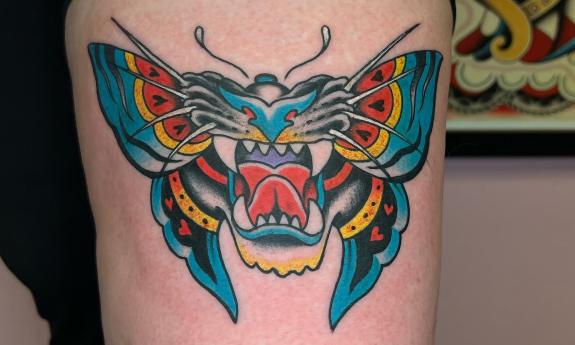 A colorful butterfly and lion tattoo