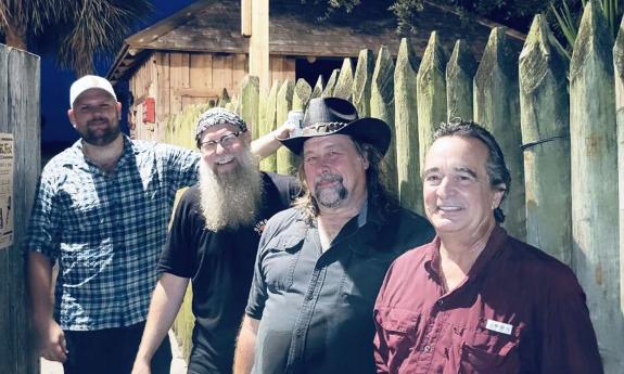 The band Muhly standing outside in front of picket fence