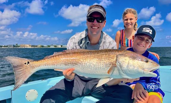 A family holding up a fresh caught fish