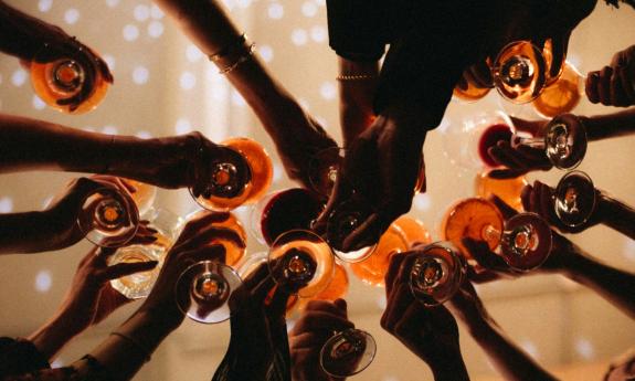 Hands raised with glasses in a toast, taken from below