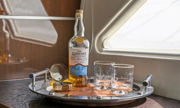 A bottle of single-malt Scotch whiskey, on a tray with glasses aboard a luxury yacht