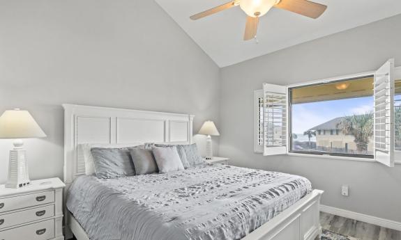 A serene master stateroom in grey and cream, with a window view of the beach