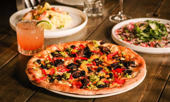 Wood-fired pizzas and a cocktail placed on the table