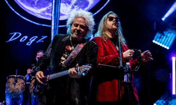 Bandmates from Toto smile and perform on stage.