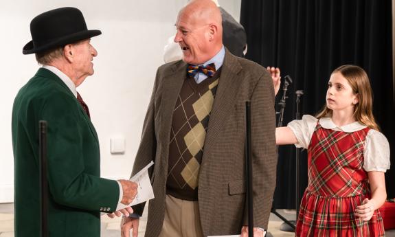 Three actors, two men and a young girl, on stage in a play rehearsal