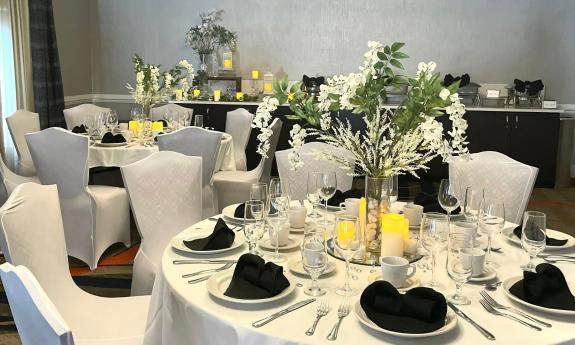 A special occassion dinner with white tablecloths, black napkins, and yellow accents
