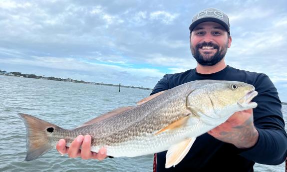 A guest holding up a freshly caught fish