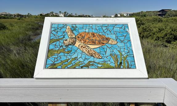 A sea turtle mosaic with the salt marsh behind