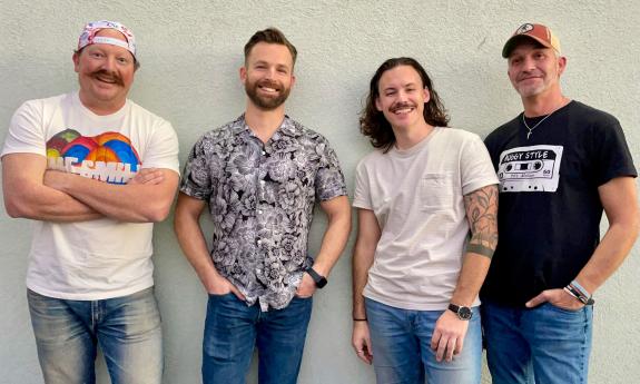 Tha band Auggy Style standing together in front of a white wall.