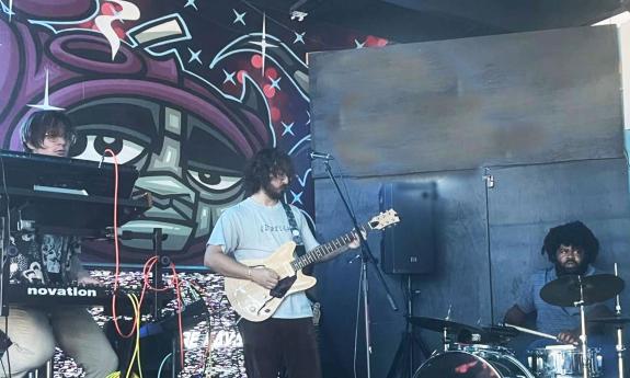 The trio band Vinegar playing onstage inside a venue