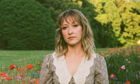 Singer and songwriter Alexa Rose standing among flowers and trees