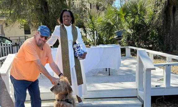 A blessing of pets, with the minister, a dog owner, and a friendly dog