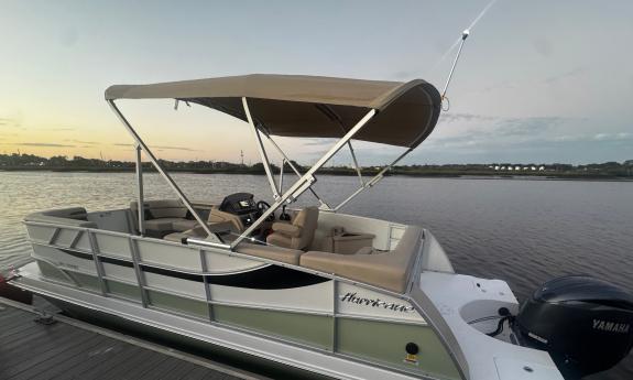 A pontoon boat, comfortable for up to 12 passengers, on the dock at sunset