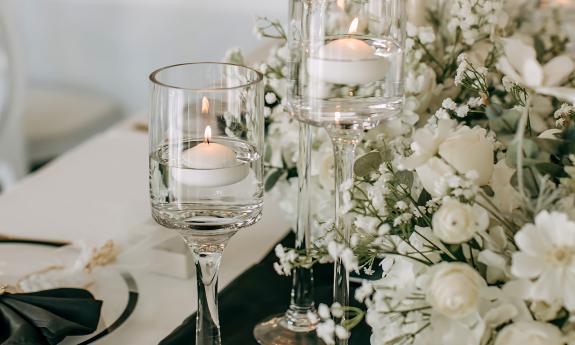 A close-up view of a table decoration with white flowers and candles in glassware