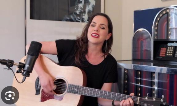 songwriter Amy Gerhartz playing her guitar, indoors