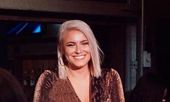 Songwriter Emma Zinck smiling, onstage at night