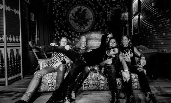 Bandmates from Flying High Again smile and pose on a couch.