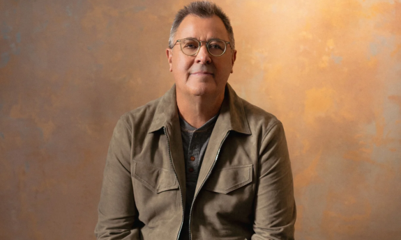 Vince Gill poses in front of a textured backdrop.