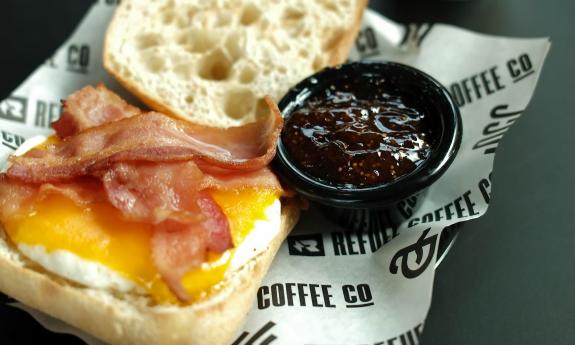 A breakfast sandwich with a side jam