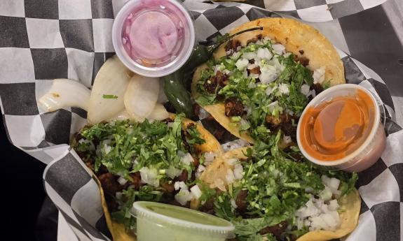 A basket of tacos with various toppings and sauces